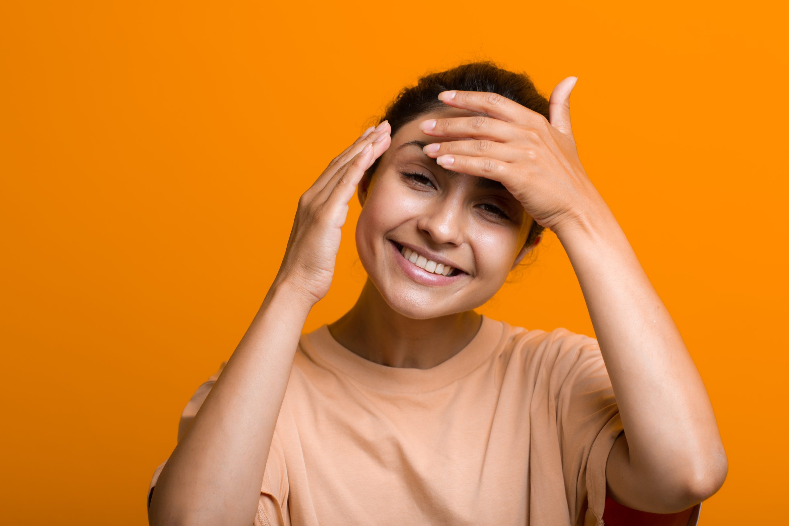 Close up portrait of young indian american woman doing facebuilding yoga face gymnastics yoga self massage.